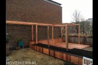 Achtertuin met houten pergola, vlonder en plantenbakken