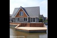 Tuin aan het water met houten beschoeiing en vlonder